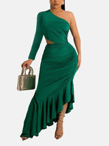 Woman wearing a green one-shoulder, long-sleeved maxi dress with a cut-out waist and ruffled asymmetrical hem, holding a gold handbag.