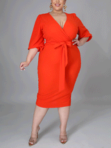 Woman wearing an orange wrap dress with a self-tie belt and puff sleeves.