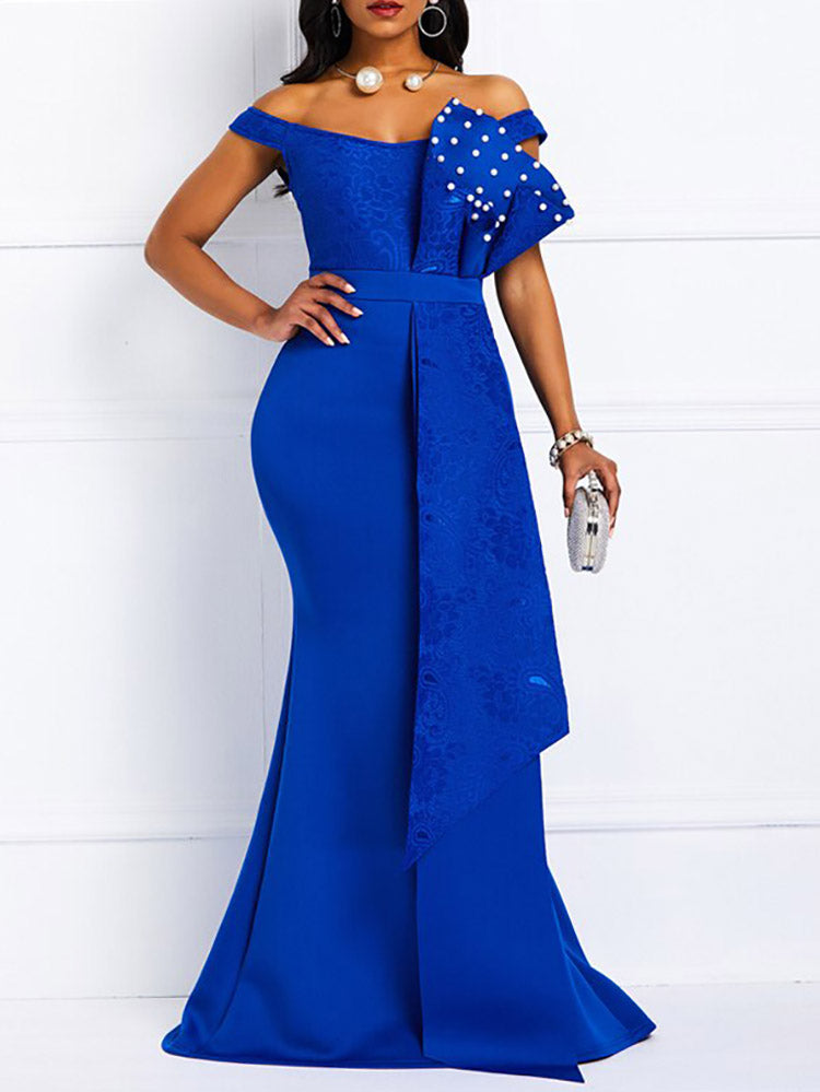 Front view of a woman in a royal blue off-the-shoulder mermaid gown with lace bodice and pearl embellishments on the ruffle.