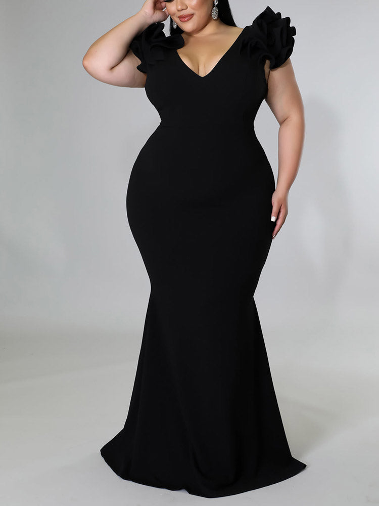 Plus-size model in a black mermaid gown with ruffled sleeves.