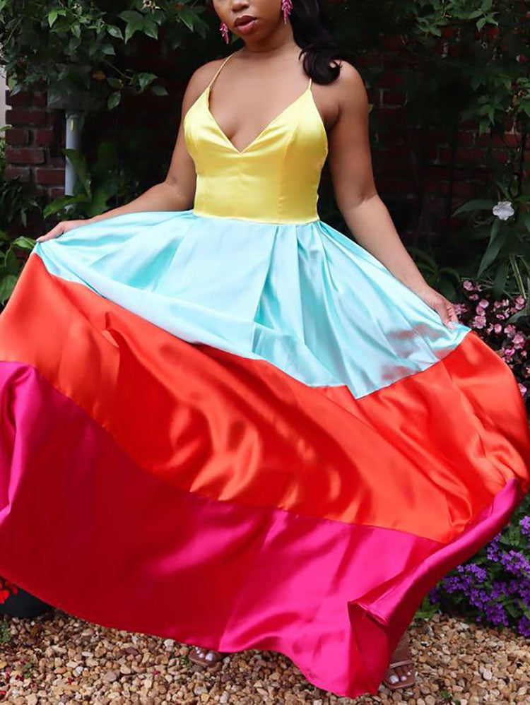 Front view of a woman wearing a yellow, light blue, orange, and pink colorblock satin maxi dress, holding the skirt.