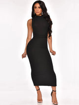 Woman wearing a black sleeveless mock neck ribbed knit sheath dress with a fitted waist and high heels, front view.