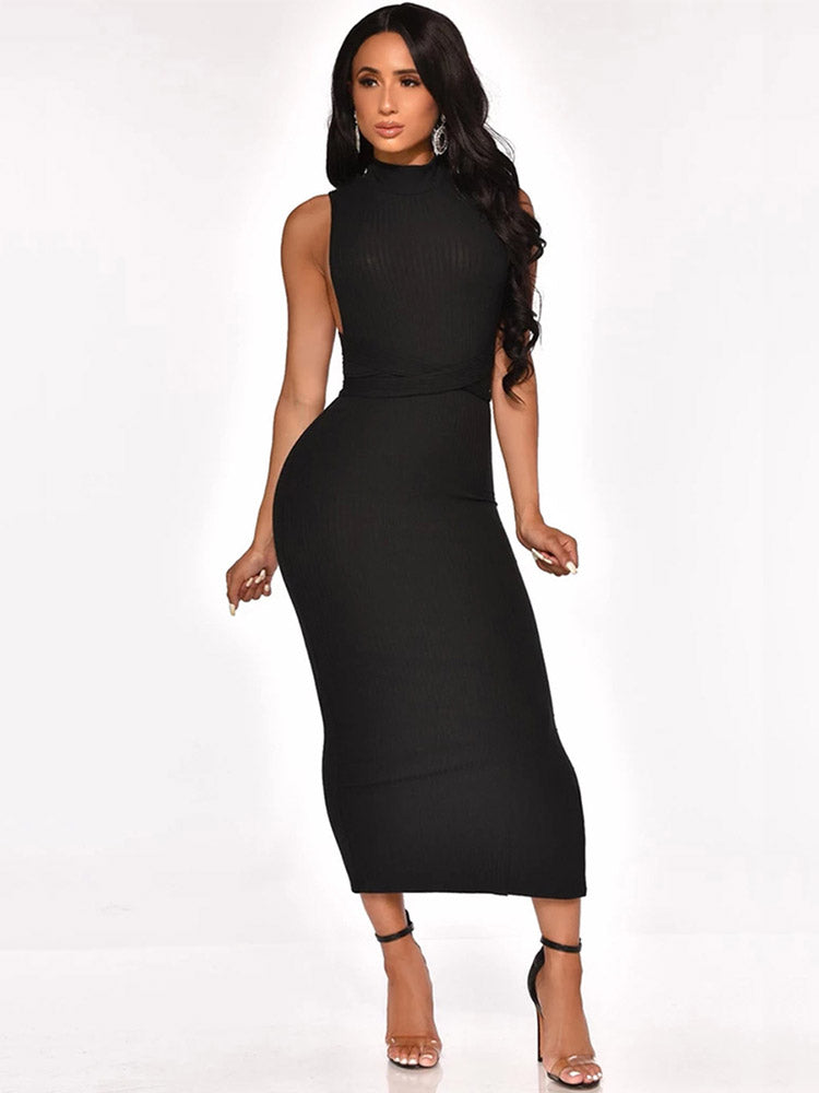 Woman wearing a black sleeveless mock neck ribbed knit sheath dress with a fitted waist and high heels, front view.