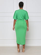 Back view of a woman wearing a green V-neck, short-sleeve, ruched, draped midi dress with a tulip hem.