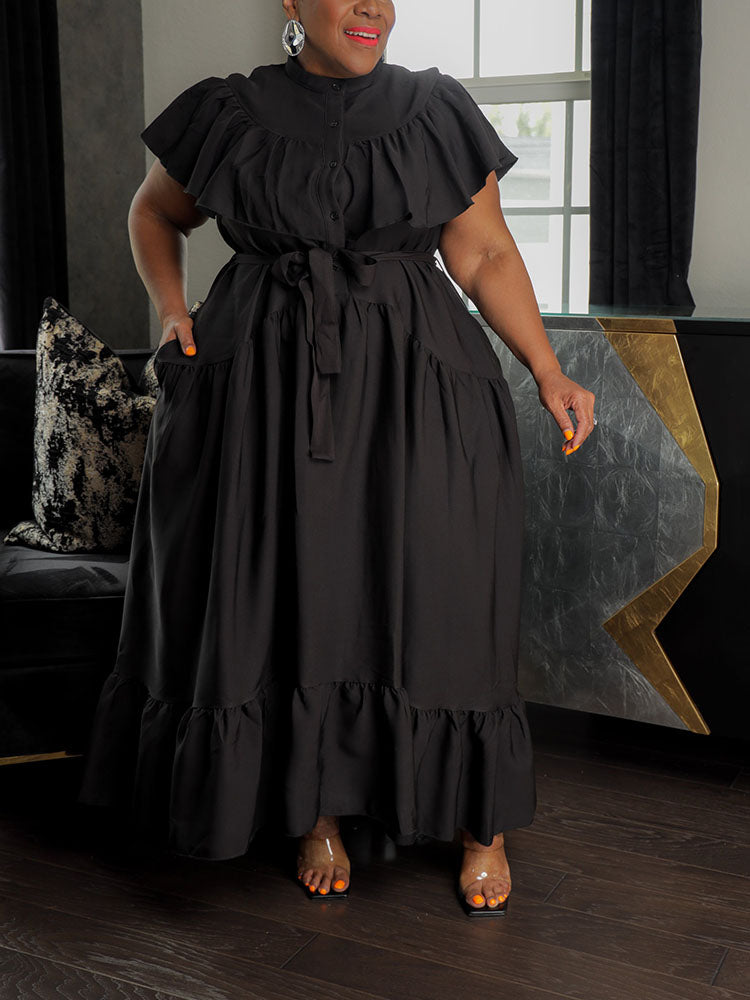Woman in a black tiered maxi dress with pockets and a belted waist.