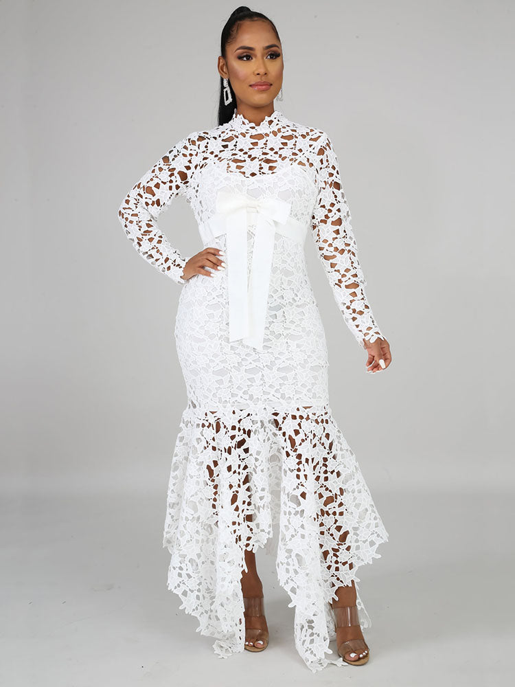 A woman in a white lace dress with a high neckline, long sleeves, and a flowing mermaid skirt.