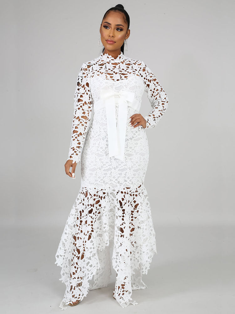 Front view of a woman wearing a white long-sleeved lace mermaid dress with a high neckline and a sash.