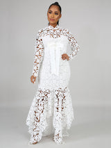 Front view of a woman wearing a white long-sleeved lace mermaid dress with a high neckline and a sash.