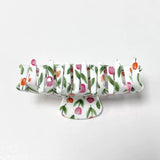 Side view of a white claw clip with a pink and orange tulip floral print, showing the teeth