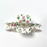 Front view of a white claw clip with a pink and orange tulip floral print, showing the hinge and teeth