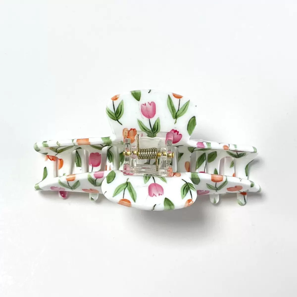 Front view of a white claw clip with a pink and orange tulip floral print, showing the hinge and teeth