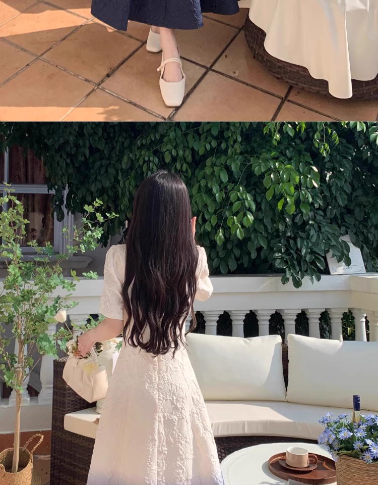 Back view of a woman wearing a white and dark blue ombre gradient fit and flare midi dress with puff sleeves, holding a bouquet of flowers.