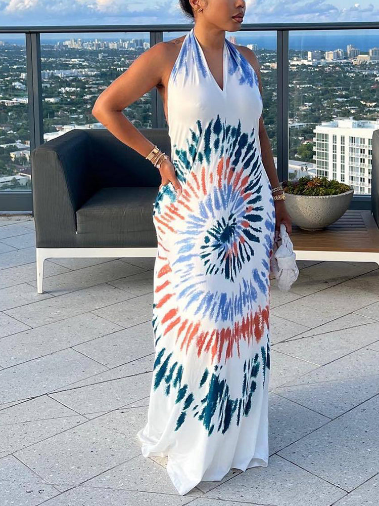 Side view of a woman in a white tie-dye maxi dress with a halter neckline.