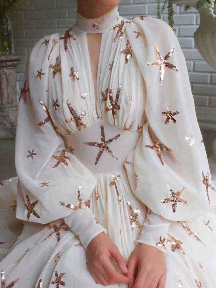 Close-up of the bodice of a white chiffon gown with starfish sequin embellishments and bishop sleeves.