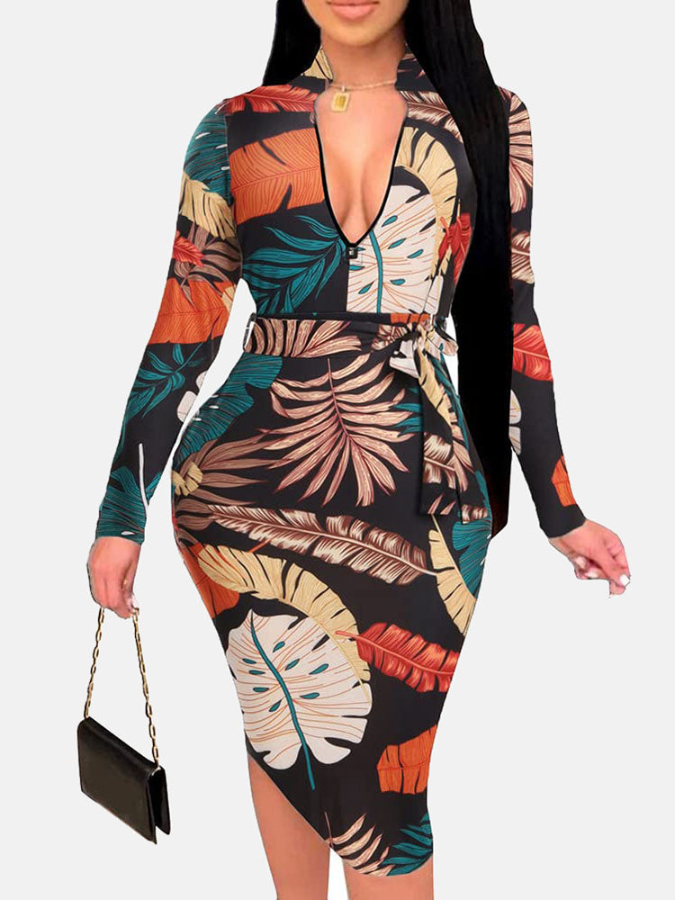 Woman wearing a black midi dress with a colorful leaf print, V-neck, long sleeves, and a belted waist.