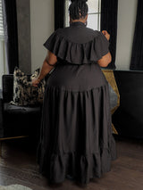 Back view of a woman in a black ruffled maxi dress.
