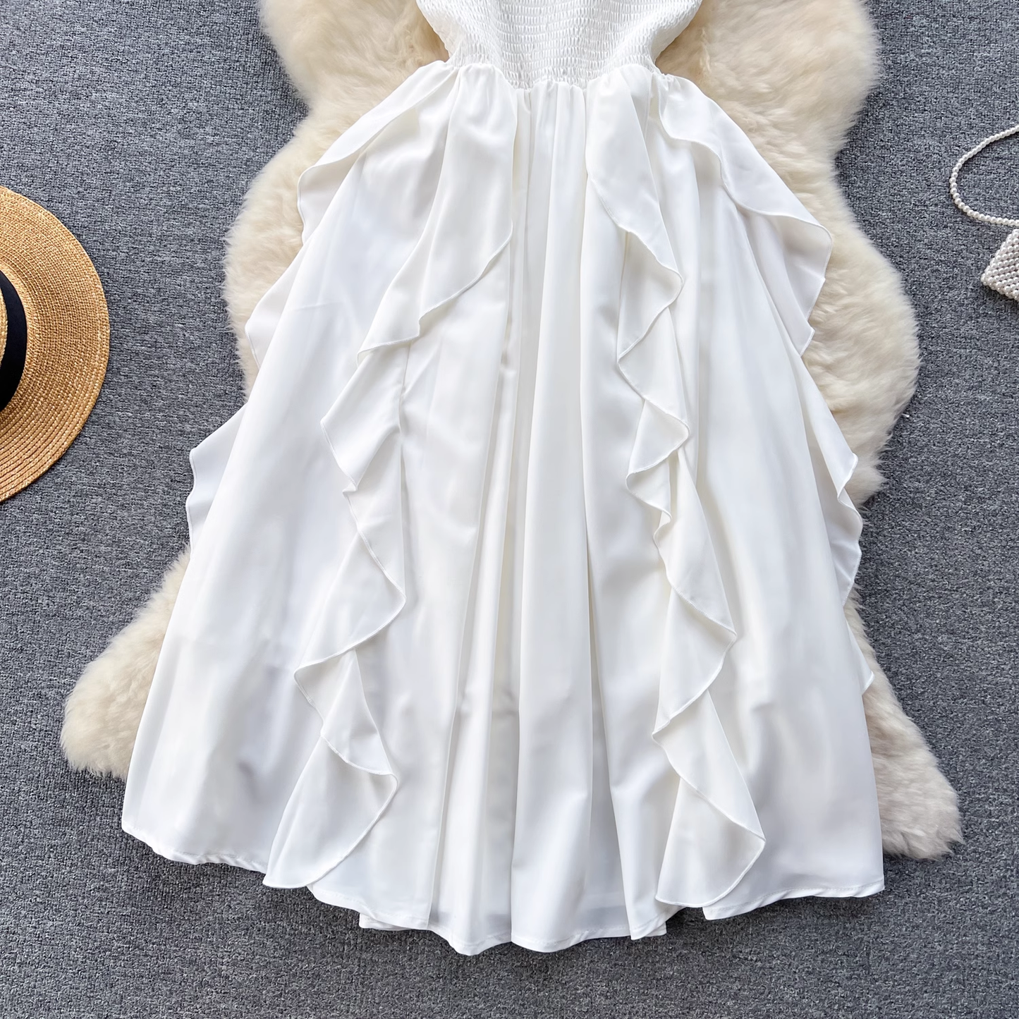 Rear view of the ruffled skirt on a white satin cami dress.