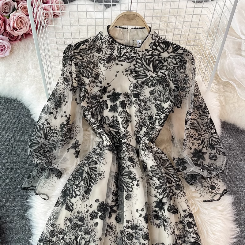 Back view of a black and white floral embroidered midi dress with sheer puff sleeves and sequin details.