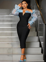 Woman in a black off-the-shoulder dress with sheer blue ruffled sleeves standing on stairs