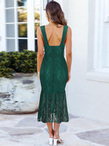Back view of a woman wearing a dark green lace midi dress with a deep V-neckline and a mermaid hem.