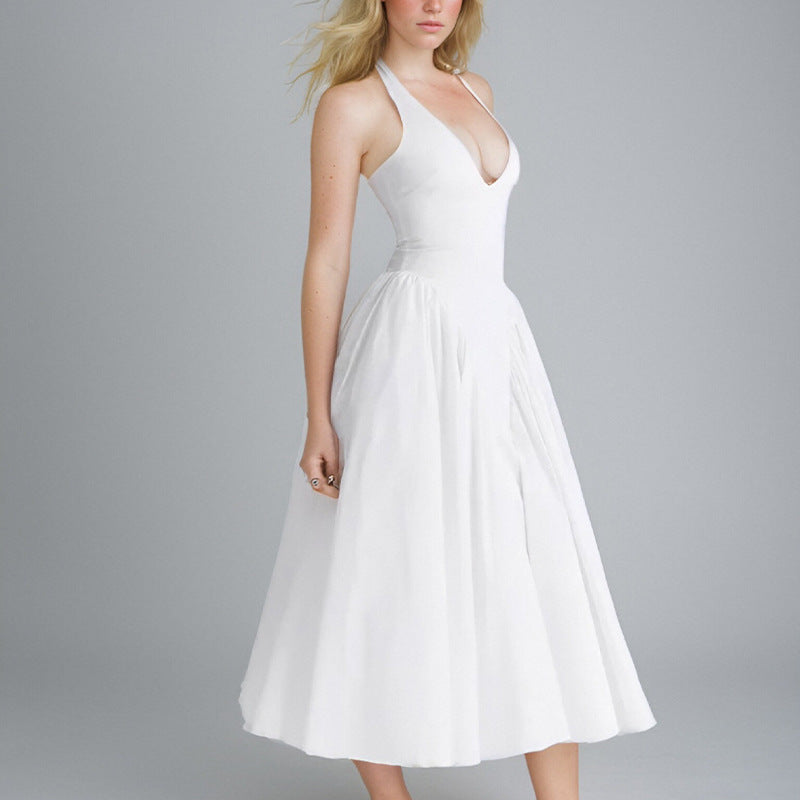 Side view of a woman modeling a white halter dress with a full, pleated skirt.