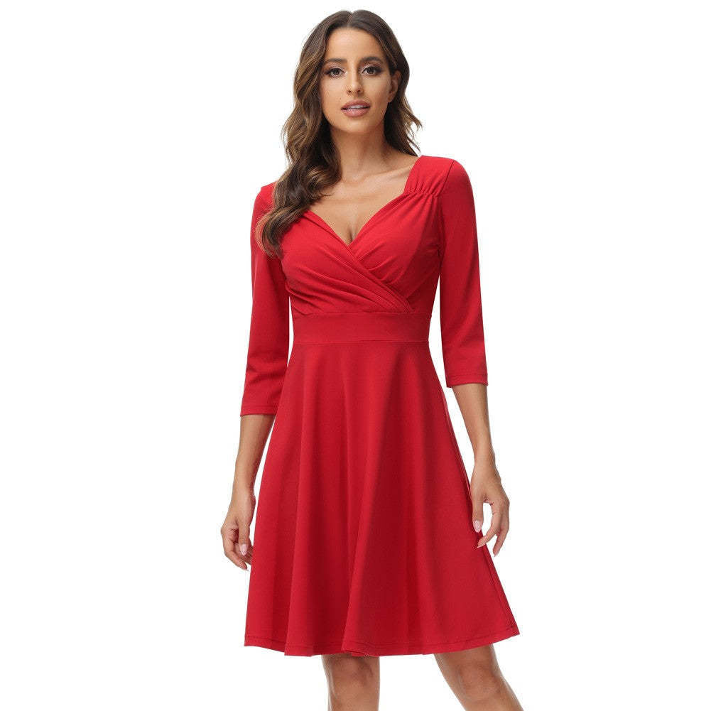Woman wearing a red fit and flare dress with a surplice neckline and three-quarter sleeves.