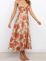 Woman wearing a floral print satin dress with a cut-out and thigh-high slit, standing with her arms outstretched.