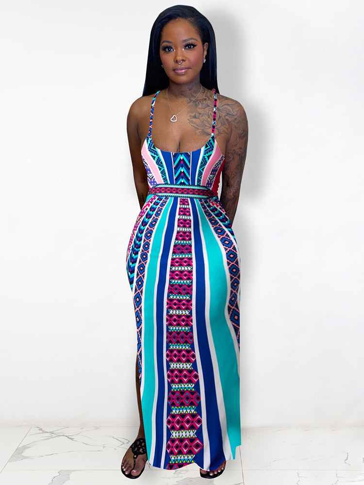 Woman with tattoos wearing a colorful geometric print maxi dress with spaghetti straps and a side slit.