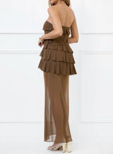 Woman wearing a brown strapless maxi dress with tiered ruffles and a sheer overlay, back view.
