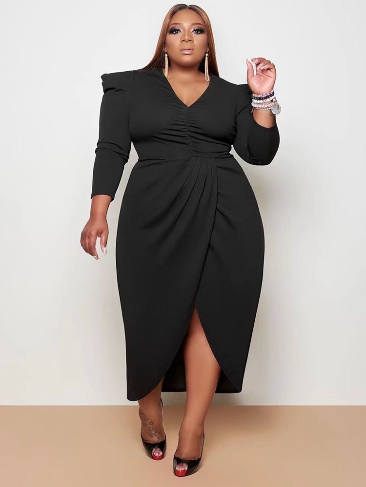 Woman wearing a black ruched V-neck sheath dress with an asymmetrical tulip hem and puffed shoulders.