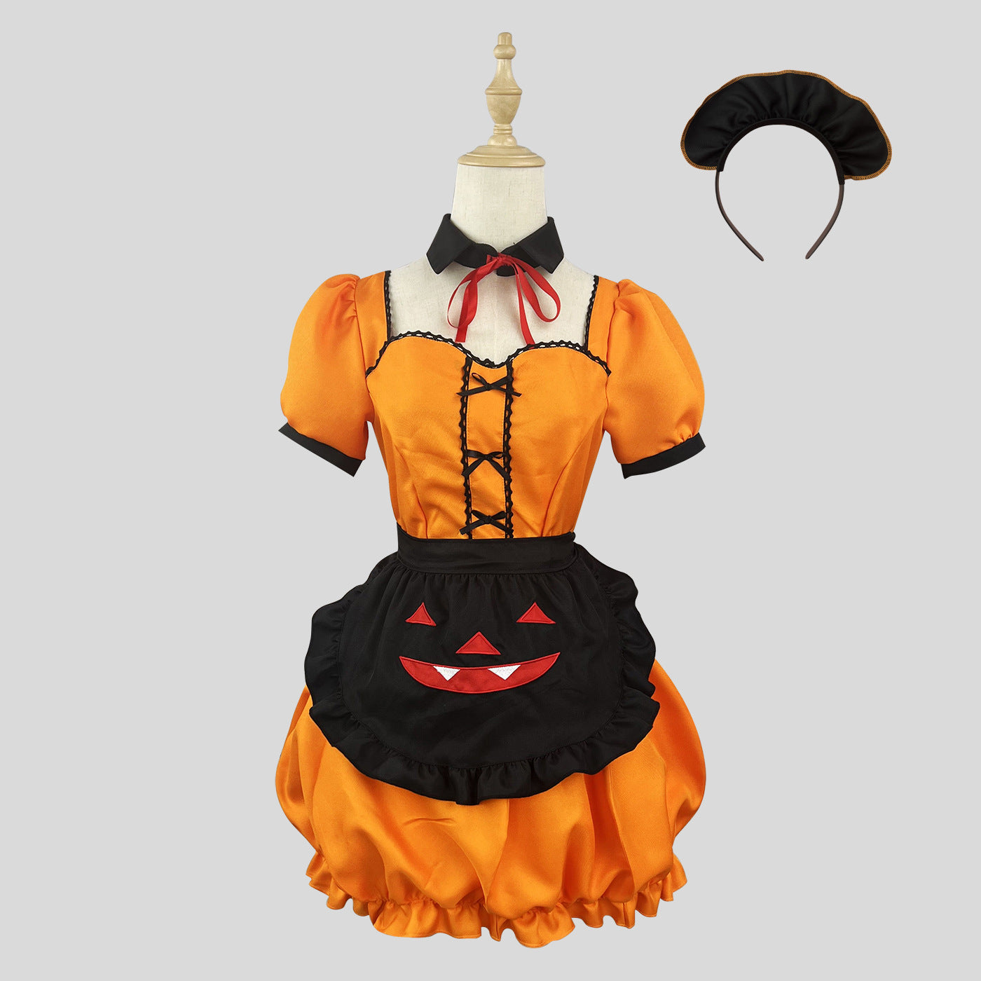 Full view of an orange Halloween costume with a black apron and a matching headband, on a mannequin against a grey background