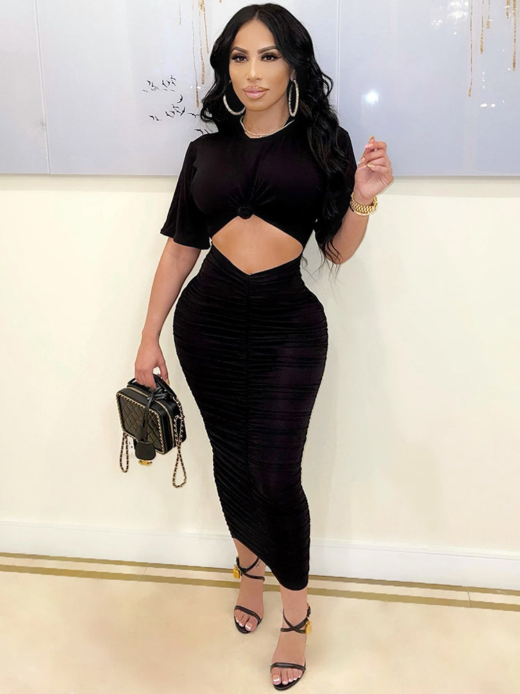 woman wearing a black ruched midi dress with a twisted crop top
