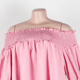 Close-up of the smocked bust and ruffle detail on a pink off-the-shoulder dress.