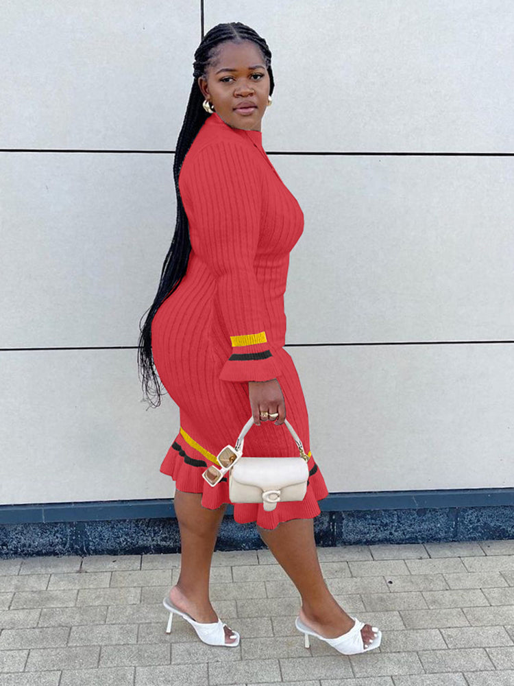 Side view of a woman in a red ribbed knit midi dress with striped accents, walking.