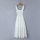 Back view of a white eyelet maxi dress hanging on a wooden hanger against a grey background