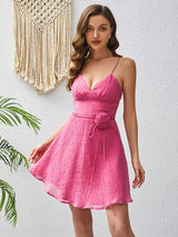 Close-up of a woman wearing a pink mini dress with spaghetti straps and a v-neckline.