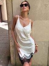 Woman wearing a white slip dress with black lace trim and sunglasses