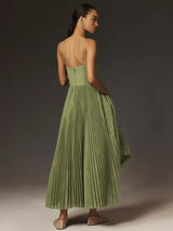 Rear view of a woman wearing a green pleated midi dress with spaghetti straps and a sweetheart neckline, showing the back of the dress.