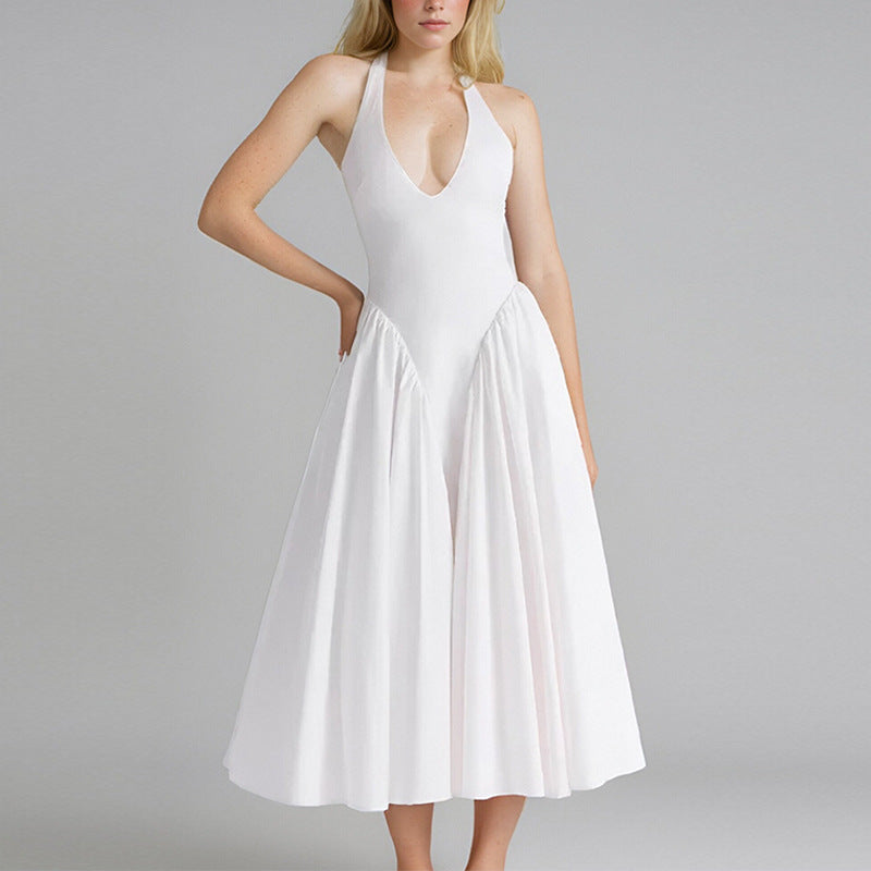 Woman wearing a white halter neck midi dress with a deep V-neckline and full skirt, standing against a gray background.