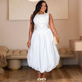 Woman in a white midi dress adorned with multiple strands of pearls.