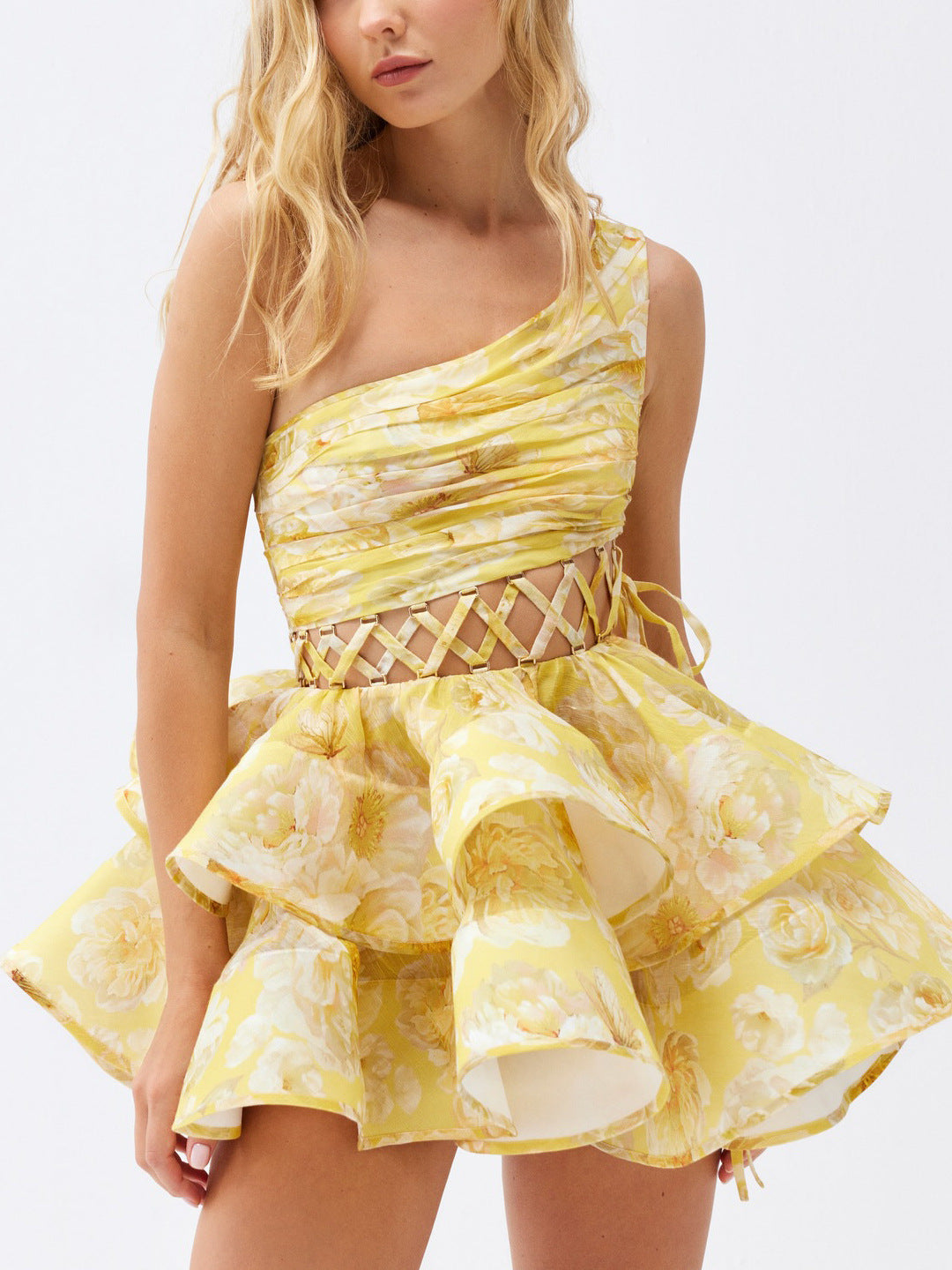 Close-up of a yellow floral print one-shoulder mini dress with a ruffled tiered skirt and lace-up waist detail.