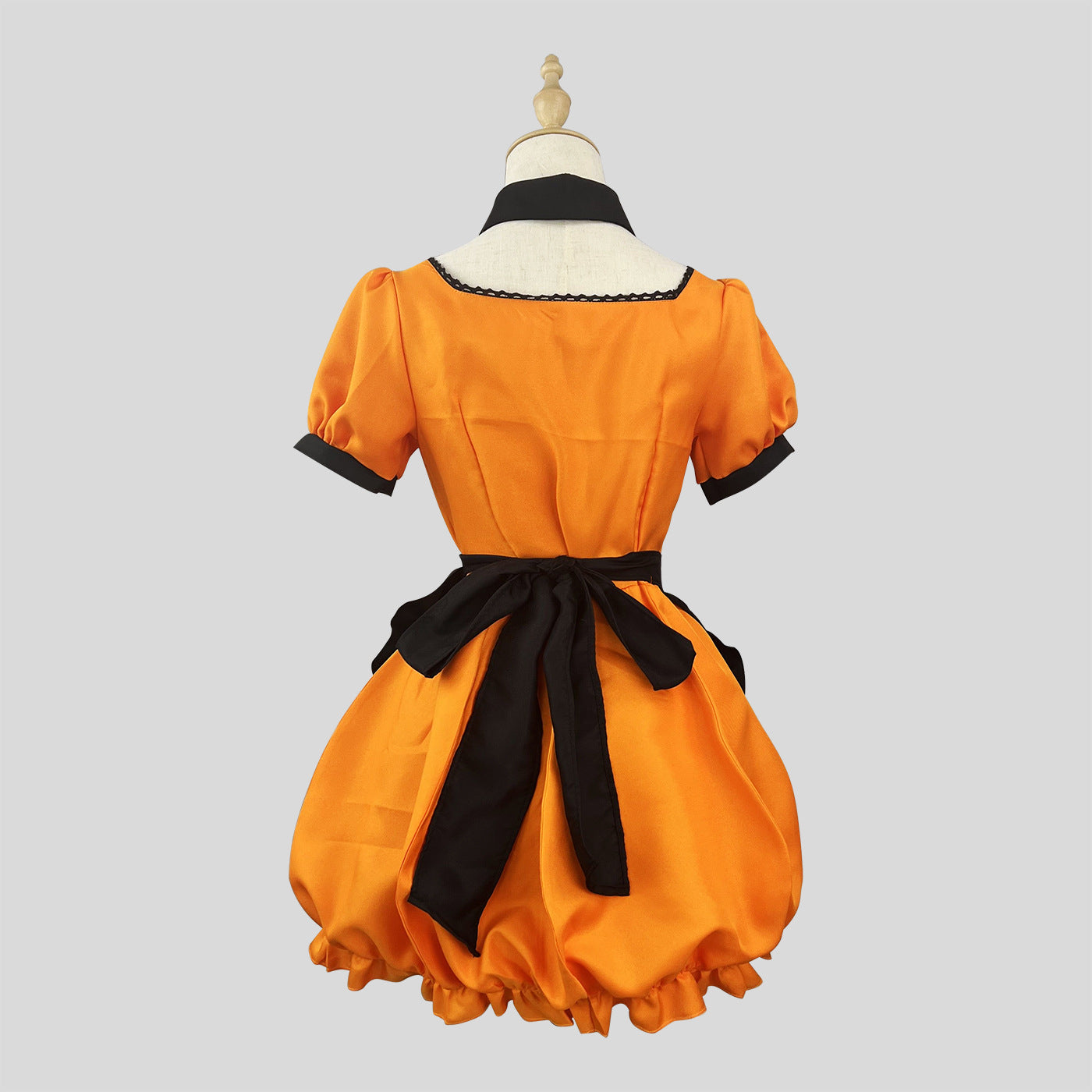 Back view of the orange Halloween costume, showing a black bow tied at the waist, on a mannequin against a grey background