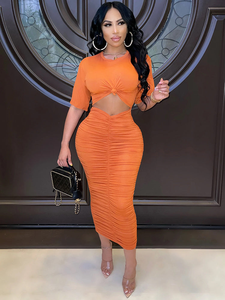 woman wearing an orange ruched midi dress with a twisted crop top