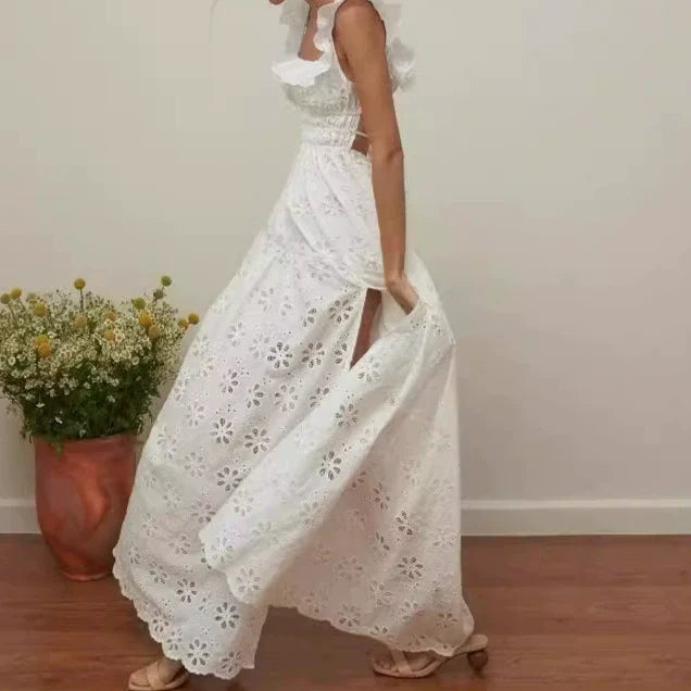 Woman in a white eyelet maxi dress with a high slit, walking and holding the skirt