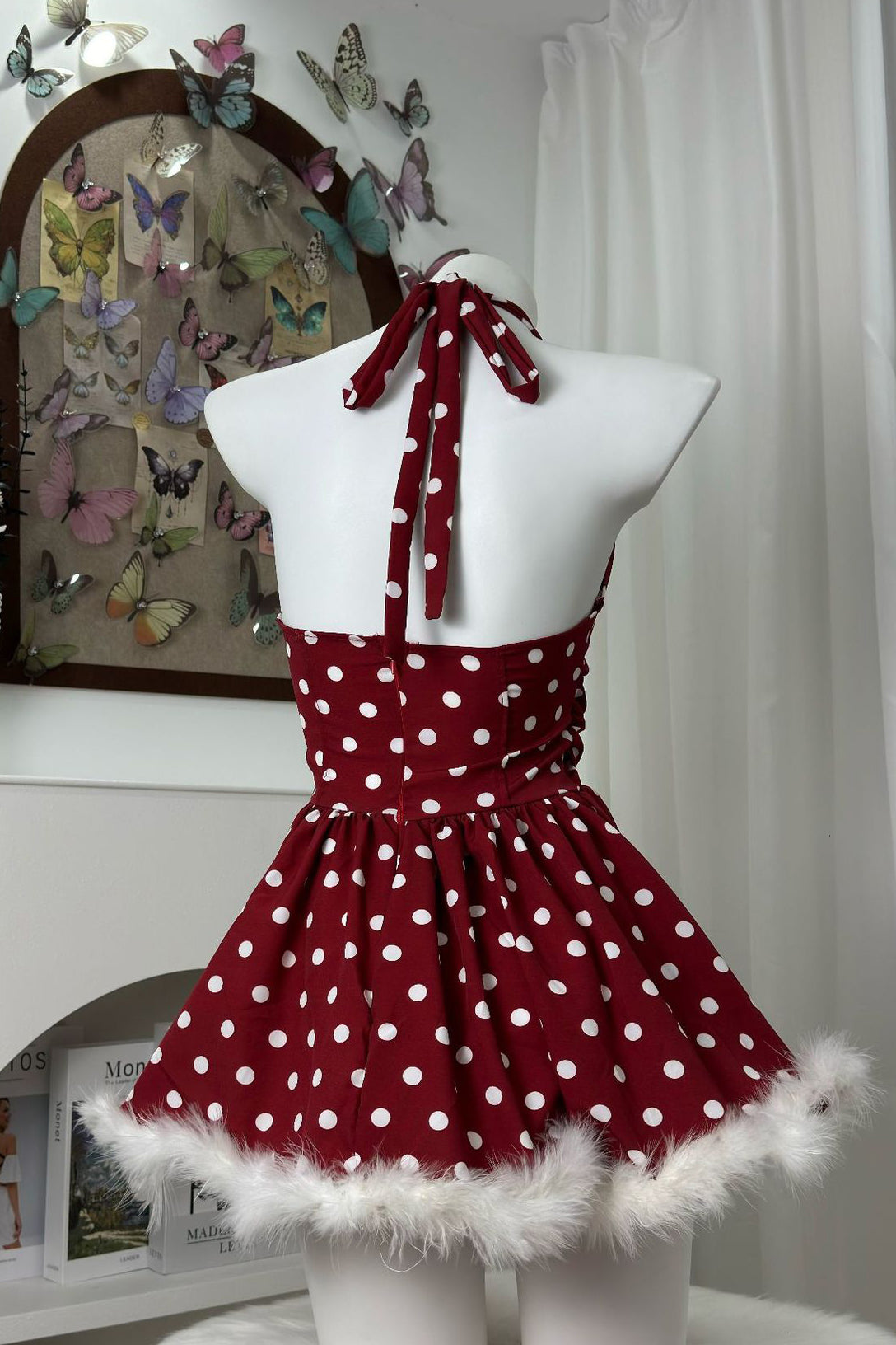 back view of a red and white polka dot halter dress with faux fur trim on a mannequin