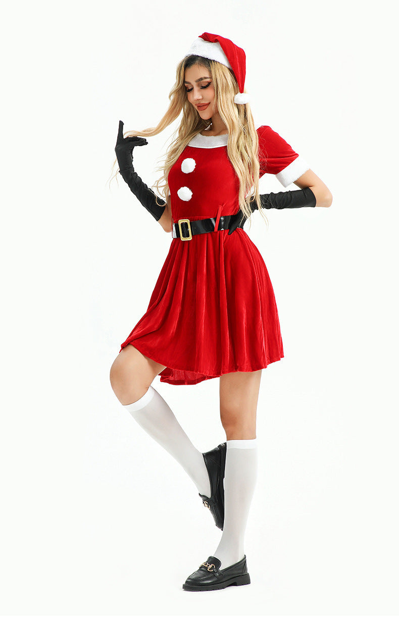 Woman in a playful pose wearing a red velvet Christmas dress, white knee-high socks, and black loafers.