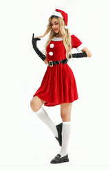 Woman in a playful pose wearing a red velvet Christmas dress, white knee-high socks, and black loafers.