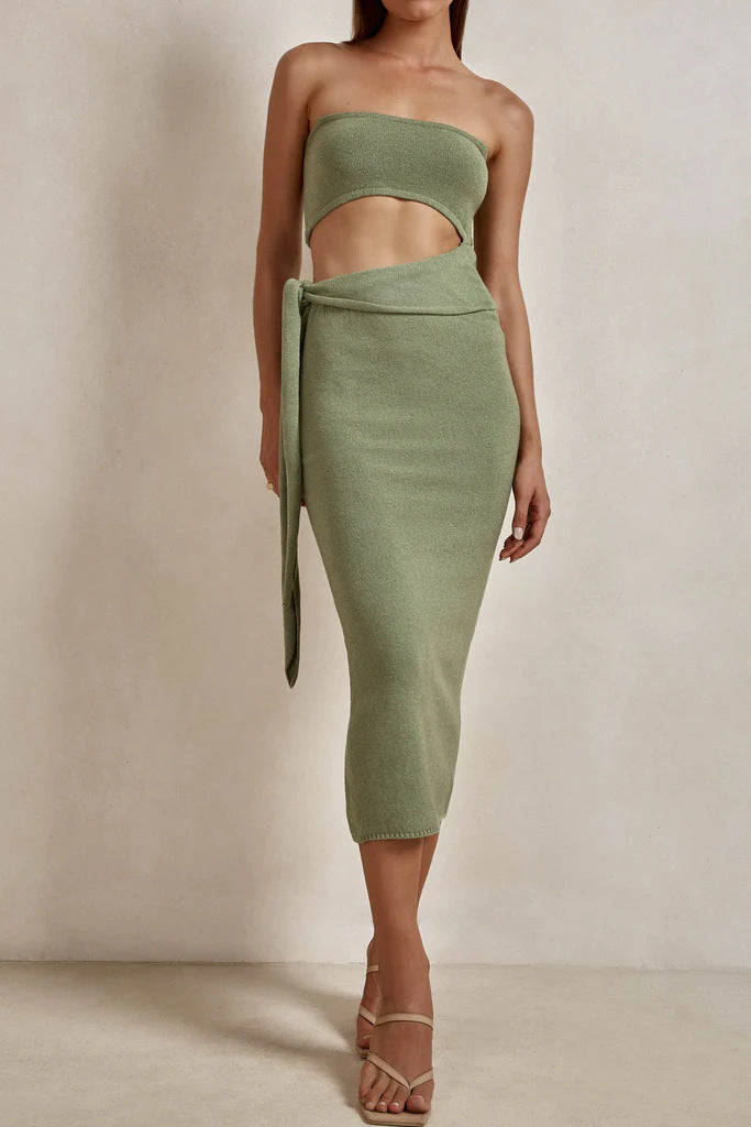 Woman wearing a sage green strapless knit crop top and matching midi skirt with a tie waist and side slit.