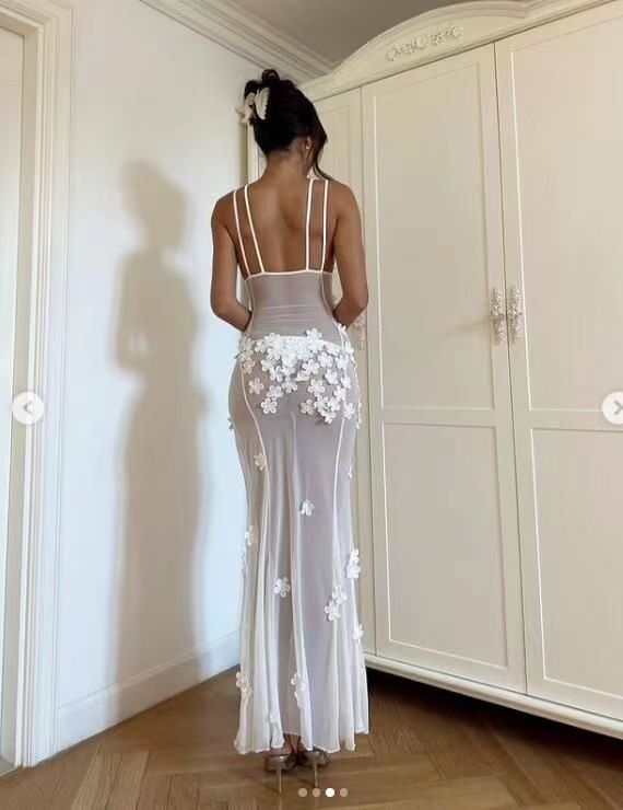 Rear view of a woman in a long, sheer white floral applique dress.