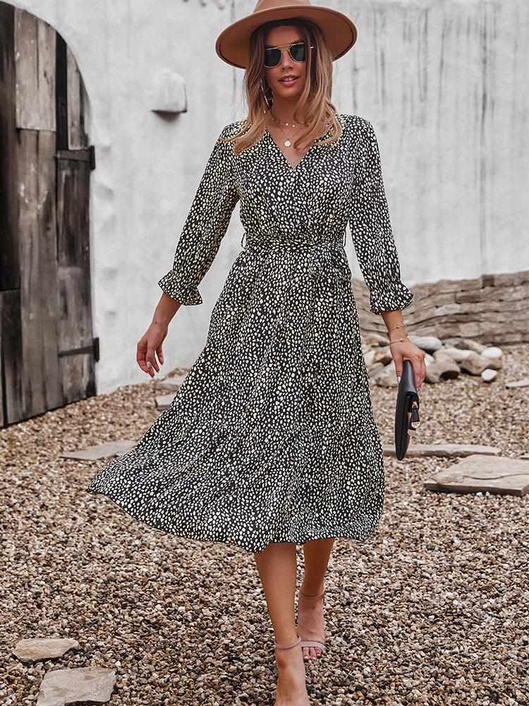 Woman twirling in a black and yellow polka dot midi dress, brown hat, and sunglasses.